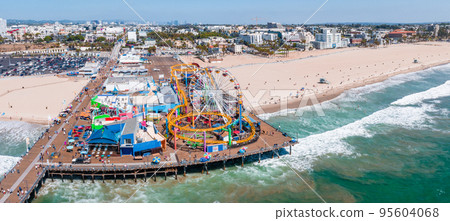 Famous Santa Monica ferris wheel amusement park in sunset light. Panoramic view of the Santa Monica Beach and the Pier Famous Santa Monica ferris wheel amusement park in sunset light. Panoramic view of the Santa Monica Beach and the Pier 95604068