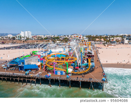 Famous Santa Monica ferris wheel amusement park in sunset light. Panoramic view of the Santa Monica Beach and the Pier Famous Santa Monica ferris wheel amusement park in sunset light. Panoramic view of the Santa Monica Beach and the Pier 95604086