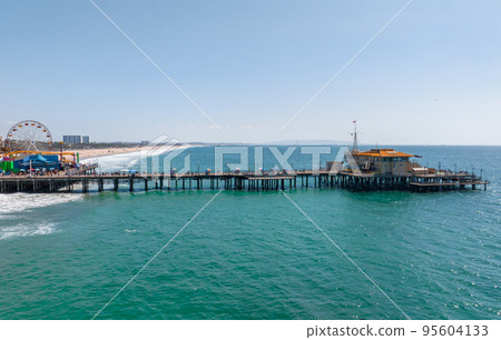 Famous Santa Monica ferris wheel amusement park in sunset light. Panoramic view of the Santa Monica Beach and the Pier Famous Santa Monica ferris wheel amusement park in sunset light. Panoramic view of the Santa Monica Beach and the Pier 95604133