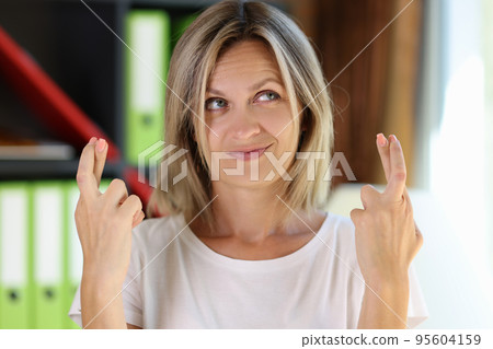 Cute smiling woman showing fingers crossed gesture Cute smiling woman showing fingers crossed gesture 95604159