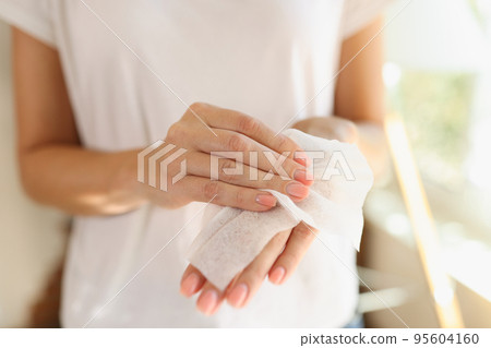 Woman cleaning hands using antibacterial wet wipes 95604160