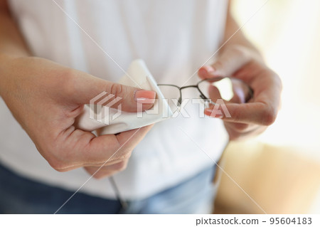 Woman wiping glasses with white cleaning napkin Woman wiping glasses with white cleaning napkin 95604183