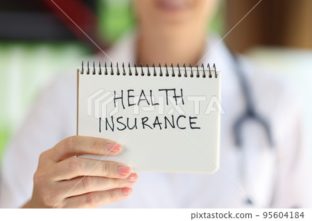 Female hand holding notepad with health insurance lettering Female hand holding notepad with health insurance lettering 95604184