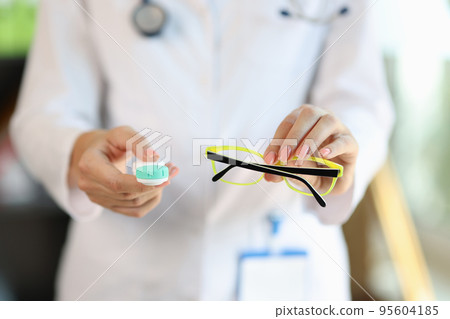 Woman doctor holding glasses and contact lens case Woman doctor holding glasses and contact lens case 95604185