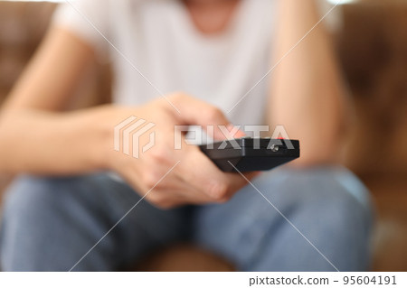 Female hand holding tv remote control and surfing programs on television Female hand holding tv remote control and surfing programs on television 95604191