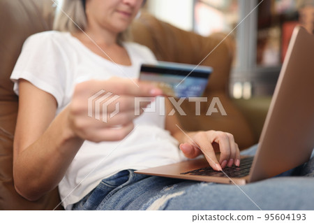 Young woman holding bank card and making online order Young woman holding bank card and making online order 95604193