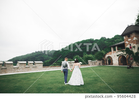 Happy wedding couple walking in a botanical park Happy wedding couple walking in a botanical park 95604428