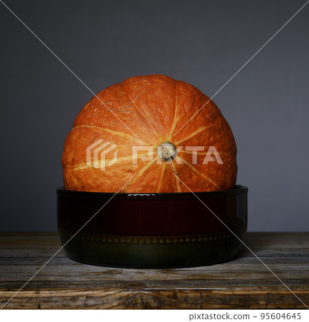 orange Hokkaido pumpkin in a ceramic bowl 95604645