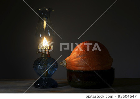 orange Hokkaido pumpkin in a ceramic bowl and a burning oil lamp orange Hokkaido pumpkin in a ceramic bowl and a burning oil lamp 95604647
