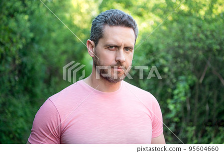 Portrait of handsome unshaven man natural background outdoors 95604660