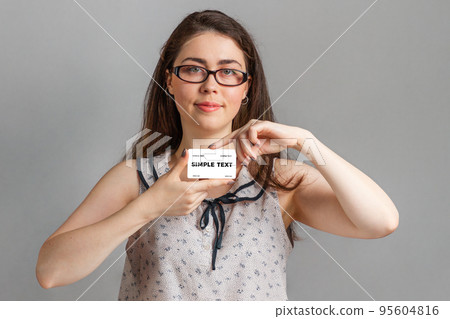 Bank investments and cards. A young woman in a blouse and glasses holds a Bank card defiantly with both hands. Copy space Bank investments and cards. A young woman in a blouse and glasses holds a Bank card defiantly with both hands. Copy space 95604816