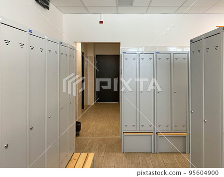 Metal lockers for clothes and benches in the locker room in the gym or at work at the enterprise for changing clothes for visitors or workers Metal lockers for clothes and benches in the locker room in the gym or at work at the enterprise for changing clothes for visitors or workers 95604900