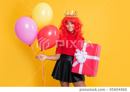 smiling kid in crown with present box and party balloon on yellow background smiling kid in crown with present box and party balloon on yellow background 95604988