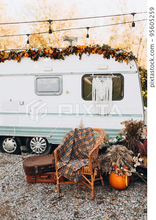 Wooden chair placed outside cozy retro caravan on autumn day in countryside. Camping life concept Wooden chair placed outside cozy retro caravan on autumn day in countryside. Camping life concept 95605259