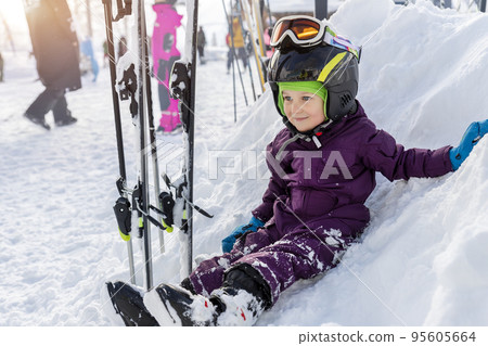Cute adorable little kid boy enjoy having fun sledging down hill of snow heap snowdrift at alpine mountain skiing resort on bright winter day. Toddler beginner skier rest of training in ski school Cute adorable little kid boy enjoy having fun sledging down hill of snow heap snowdrift at alpine mountain skiing resort on bright winter day. Toddler beginner skier rest of training in ski school 95605664