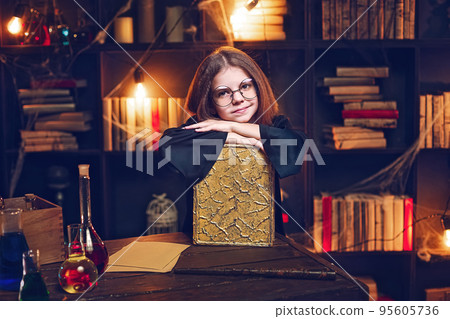 Small girl witch in glasses holds magic book Cosplay. Halloween party, costume, holiday Small girl witch in glasses holds magic book Cosplay. Halloween party, costume, holiday 95605736