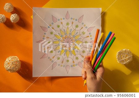 Female painting mandalas antistress page to combat stress. Relaxing hobby mental wellbeing and art therapy. Woman paints sketch, meditative process of coloring pages. Self expression by art  95606001