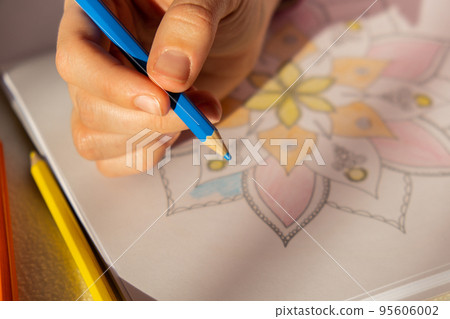 Female painting mandalas antistress page to combat stress. Relaxing hobby mental wellbeing and art therapy. Woman paints sketch, meditative process of coloring pages. Self expression by art  95606002