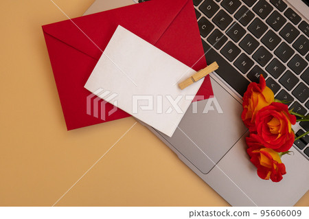 Beautiful red roses flowers in postal red envelope on neutral beige background, laptop keyboard technology online empty paper note copy space for text, spring time, greeting card for holiday. Flower Beautiful red roses flowers in postal red envelope on neutral beige background, laptop keyboard technology online empty paper note copy space for text, spring time, greeting card for holiday. Flower 95606009