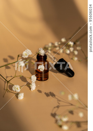 Small bottle of serum on neutral beige background. Beauty pipette dropper with Gypsophila or baby's breath white flowers. Glass dropper of cosmetic oil and dried flowers and herbs. Natural organic Small bottle of serum on neutral beige background. Beauty pipette dropper with Gypsophila or baby's breath white flowers. Glass dropper of cosmetic oil and dried flowers and herbs. Natural organic 95606034