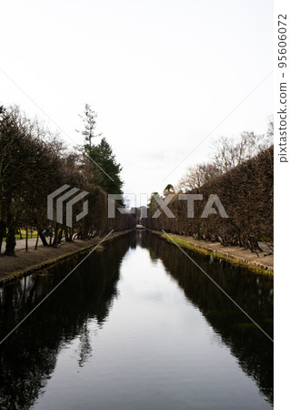 Beautiful spring lake way in two sides and forest. Springtime season Abstract natural background. Blurry silhouettes of many green spring trees, leaves reflect on peaceful surface of river, lake or 95606072