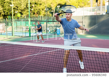 Young teenage player training on court. Boy using racket to hit ball 95606340