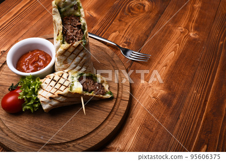Minced meat wrapped with lavash bread on wooden background. 95606375