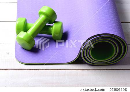 Healthy shape and sport concept. Barbells on rolled yoga mat Healthy shape and sport concept. Barbells on rolled yoga mat 95606398