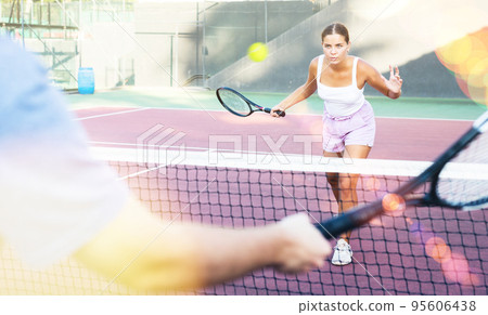Focused young woman playing friendly tennis match. Concept of concentration in competition Focused young woman playing friendly tennis match. Concept of concentration in competition 95606438