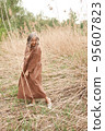 Beautiful girl in a linen dress in the forest. Amazing summer nature. Travel concept. Inspiration for wanderlust. Woman in linen brown dress. Eco-friendly materials for clothes. 95607823