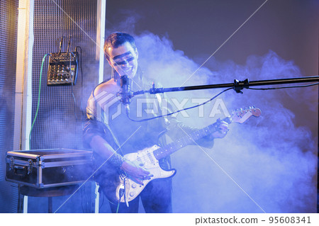 Talented artist performing heavy metal music with guitar, playing cool stylish song with instrument. Doing live show in studio and singing alternative rock song with loud scream, wearing leather. Talented artist performing heavy metal music with guitar, playing cool stylish song with instrument. Doing live show in studio and singing alternative rock song with loud scream, wearing leather. 95608341