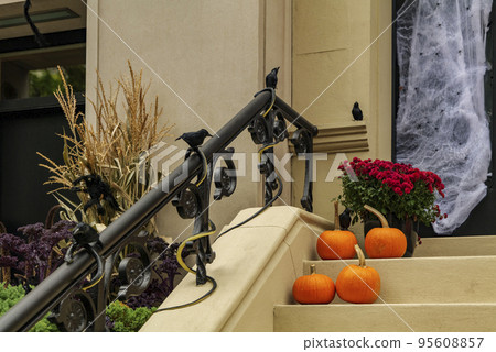 Assorted Halloween decorations guard the front steps of a house. Pumpkins on a porch. 95608857