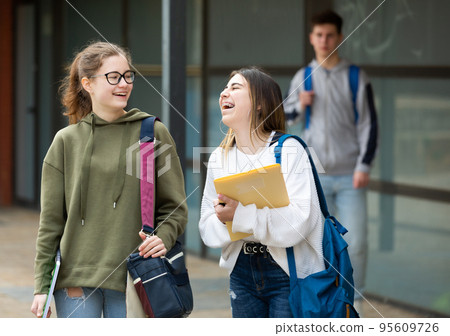 Smiling teenage girls walking after lessons Smiling teenage girls walking after lessons 95609726