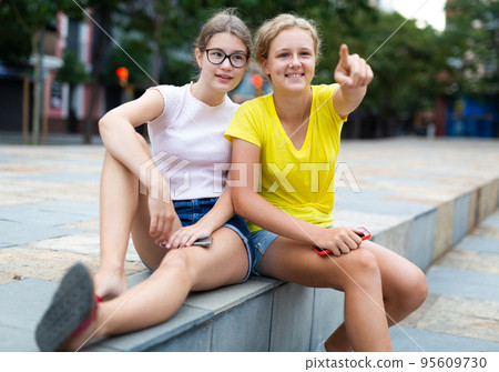 Two friendly girls sitting in square 95609730