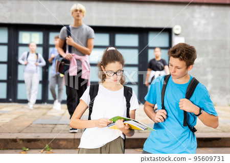 Teen girl going to lessons with classmate on autumn day 95609731