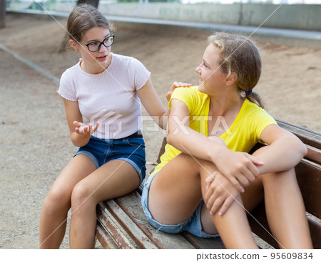 Youth girls in shorts sitting on bench Youth girls in shorts sitting on bench 95609834