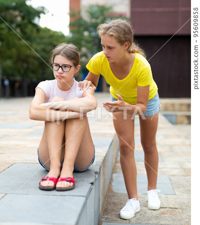 Upset young girl and her friend outdoors Upset young girl and her friend outdoors 95609858