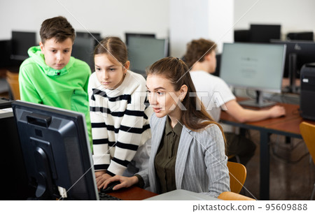 Teenagers studying with female teacher in information technology class Teenagers studying with female teacher in information technology class 95609888