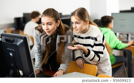 Teacher explaining task solution to pupil during computer science lesson Teacher explaining task solution to pupil during computer science lesson 95609923
