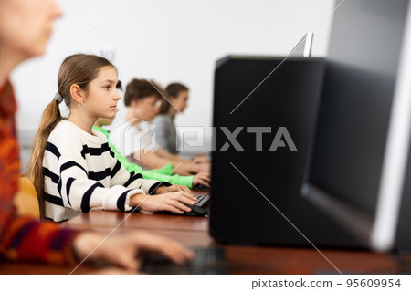 Young girl learning to use personal computer during lesson 95609954