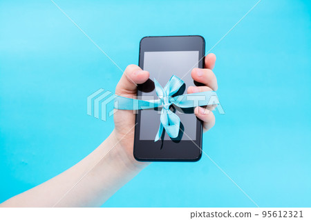 Digital detox concept. Children's hand with a smartphone tied with a blue ribbon. Gadget addiction 95612321