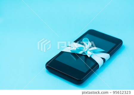 Digital detox concept. The smartphone is tied with a blue ribbon with a bow on a blue background. Gadget addiction 95612323