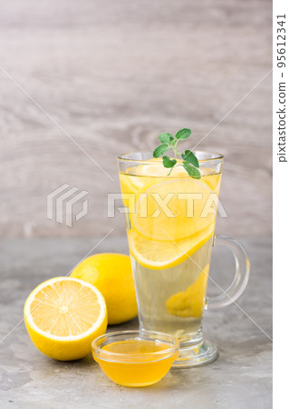 Therapeutic drink of lemon, honey and mint in a glass on the table. Alternative medicine, treatment with folk remedies. Therapeutic drink of lemon, honey and mint in a glass on the table. Alternative medicine, treatment with folk remedies. 95612341