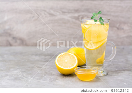 Therapeutic drink of lemon, honey and mint in a glass on the table. Alternative medicine 95612342
