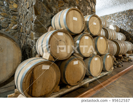 The wooden wine barrels in a wine factory The wooden wine barrels in a wine factory 95612587