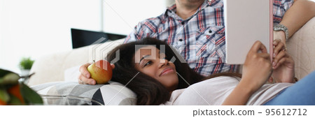 Middle aged man and young latin woman reading book together, good friends meet for fun 95612712