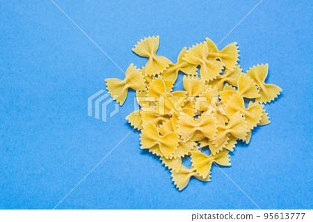 Raw farfale pasta on a blue cardboard background. Top view Raw farfale pasta on a blue cardboard background. Top view 95613777