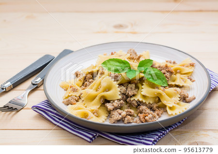 Ready-to-eat pasta navy with minced meat and basil leaves on a plate on a wooden table. Russian cuisine 95613779