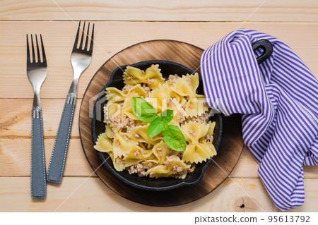 Ready-to-eat pasta navy with minced meat and basil leaves in a iron frying pan on a wooden table. Russian cuisine. Top view 95613792