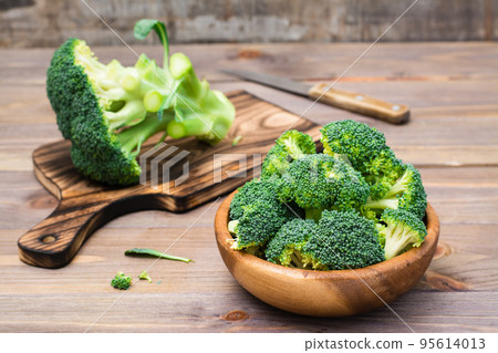 Ready to eat fresh raw broccoli is divided into inflorescences in a wooden plate and on a cutting board and a knife on a wooden table. Healthy lifestyle, nutrition and zero waste concept Ready to eat fresh raw broccoli is divided into inflorescences in a wooden plate and on a cutting board and a knife on a wooden table. Healthy lifestyle, nutrition and zero waste concept 95614013